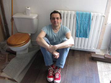 Eric pose du parquet dans une salle de bains.